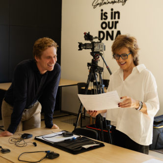 Two colleagues at a camera setup in front of the wall text Sustainability is in our DNA AirProducts
